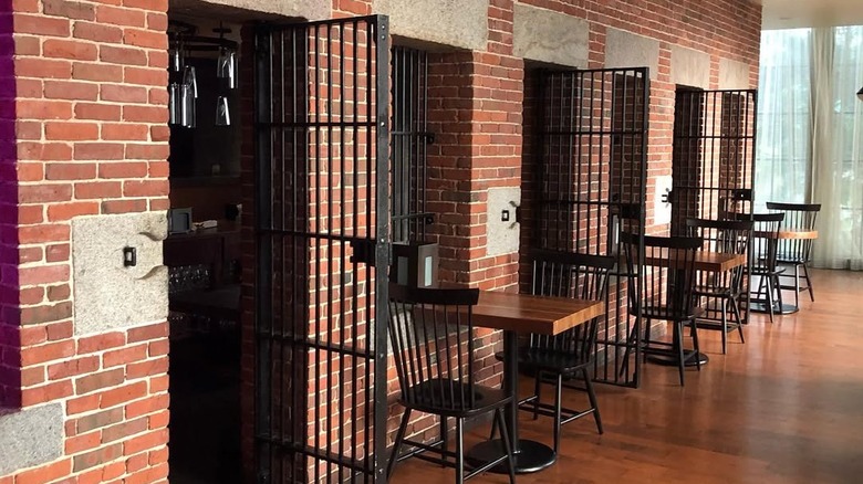 The interior of Clink. restaurant in Boston showing tables and chairs by cells