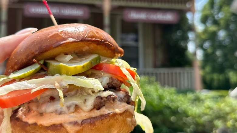 Hand holding a burger in front of Harrie's Jailhouse