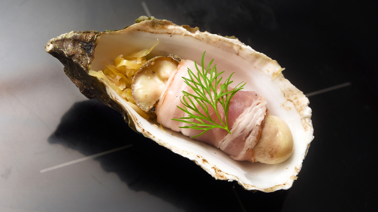 A bacon-wrapped oyster in a shell