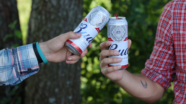 Two people clinking beer cans