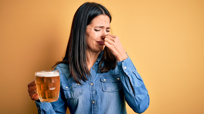 Woman refusing to drink a beer that disgusts her