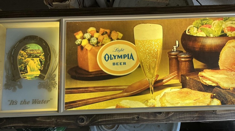 An old-fashioned Olympia Beer sign with the slogan "It's the Water"