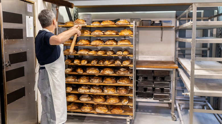 Man takes fresh bread off rack