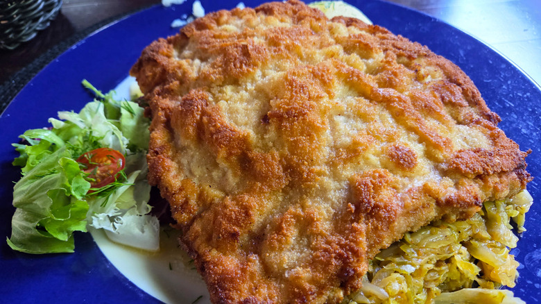 Fried schnitzel on a blue plate with a green salad