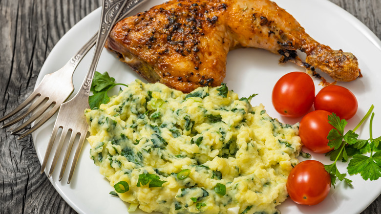 Colcannon, chicken, and tomatoes on a white plate