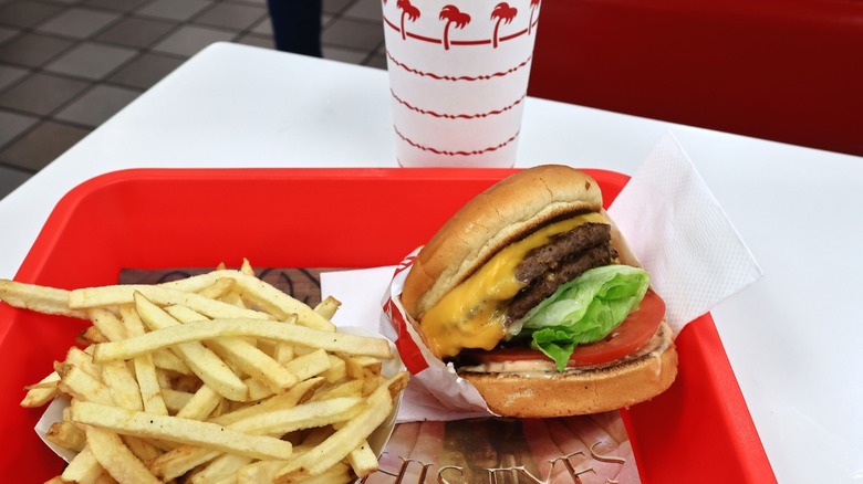 An In-N-Out burger and fries on a tray with a drink in the background