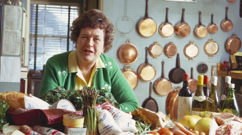 Celebrity chef Julia Child posing in front of her large collection of copper pots.