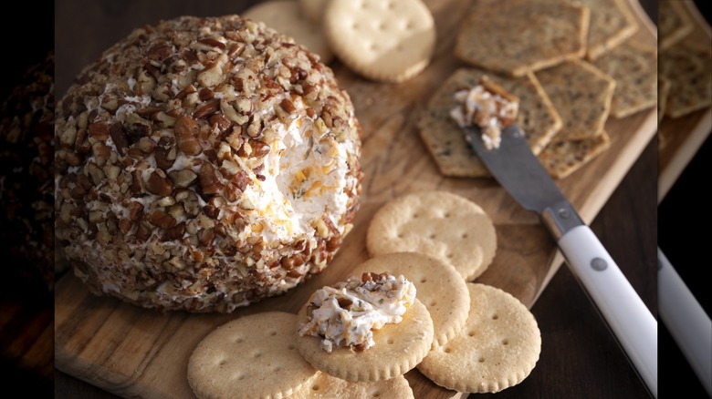Close-up of a classic cheese ball with crackers on a cutting board with cheese knife