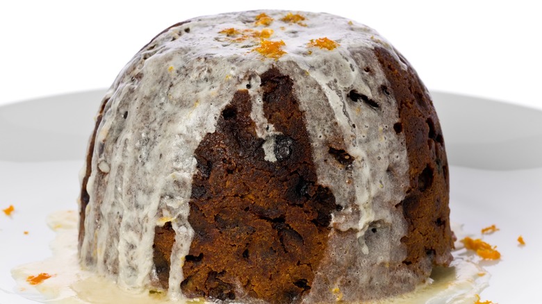 Christmas pudding with bourbon hard-sauce garnished with orange zest.