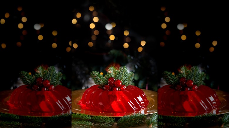 Cranberry JELL-O mold with Christmas lights in background and garnish of fresh cranberry