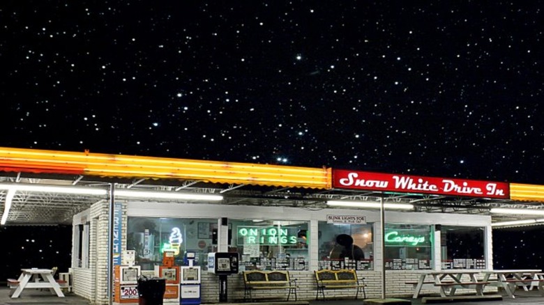 Nighttime exterior photo of Snow White Drive In with outdoor picnic tables