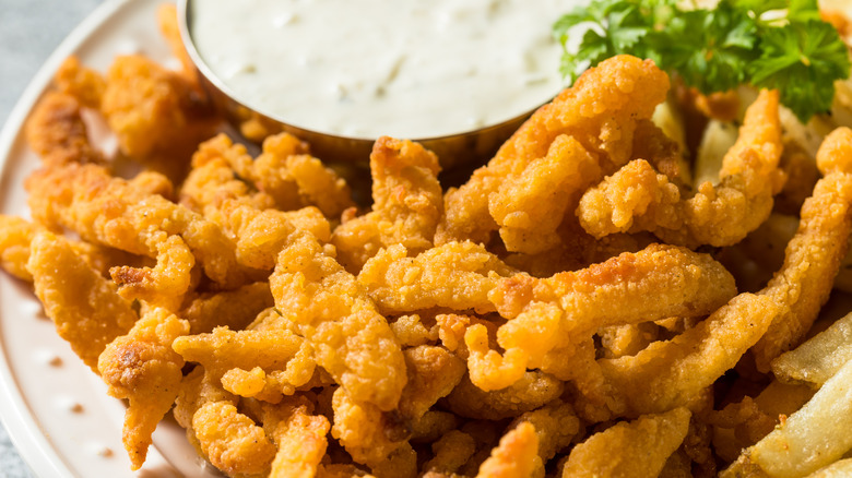 plate of fried clam strips with French fries and tartar sauce.