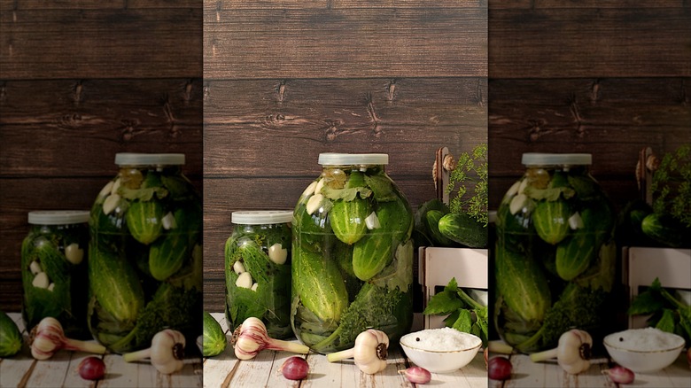 Pickled cucumbers in a jar with fresh onions on a table