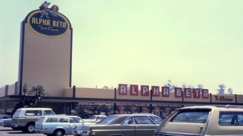 Retro photo of Alpha Beta grocery store parking lot with store signage and old cars in parking lot