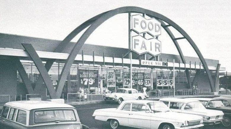 Black and white photo of Food Fair grocery store parking lot with vintage cars