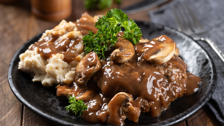 Salisbury steak on a plate with mashed potatoes, gravy  and parsley