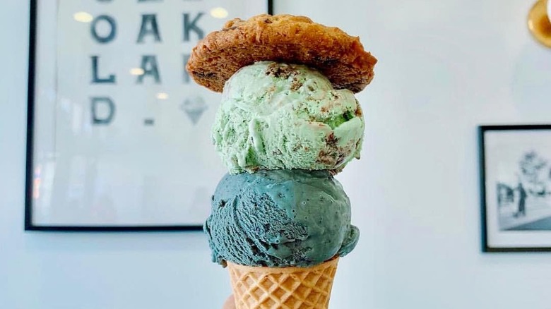 Two ice cream scoops on a waffle cone with a cookie on top