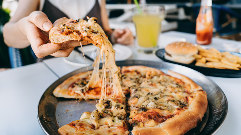 Person taking a slice of pizza from a plate on a table