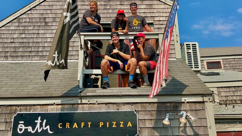 Oath Pizza employees hang out outside next to flags