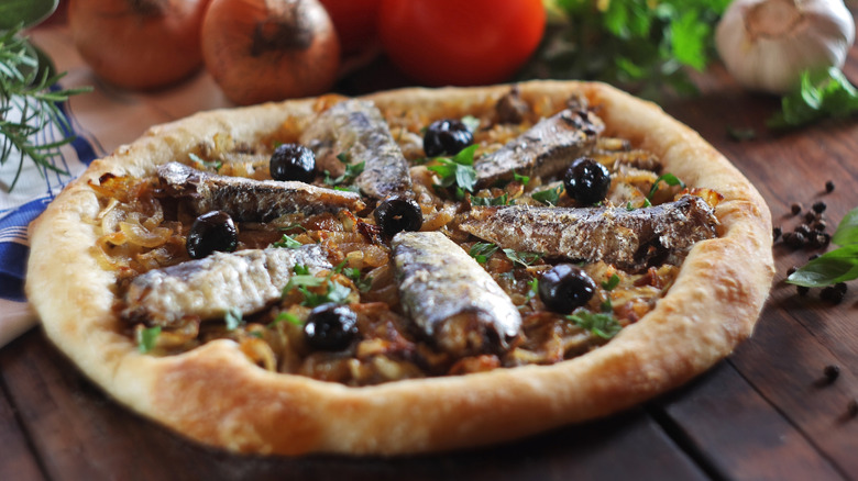 A pizza topped with sardines and black olives
