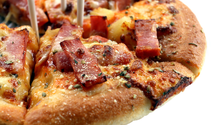 A close-up of a pizza topped with pieces of thick-cut ham or Spam