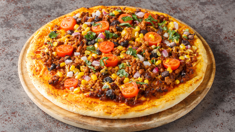 A fully loaded Tex-Mex taco pizza on a wood plate