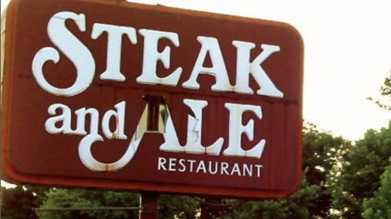 worn out Steak and Ale sign by trees