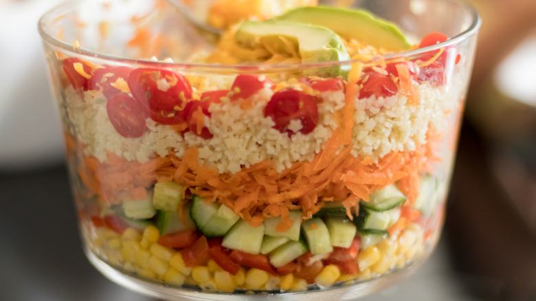 Layered vegetable salad in a clear glass bowl