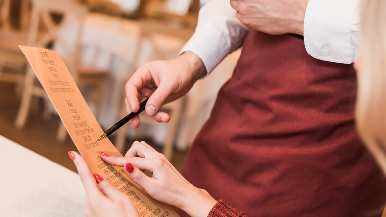 A server pointing out menu items to a customer.