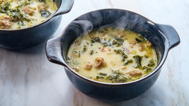Black crocks of creamy soup with meat and greens