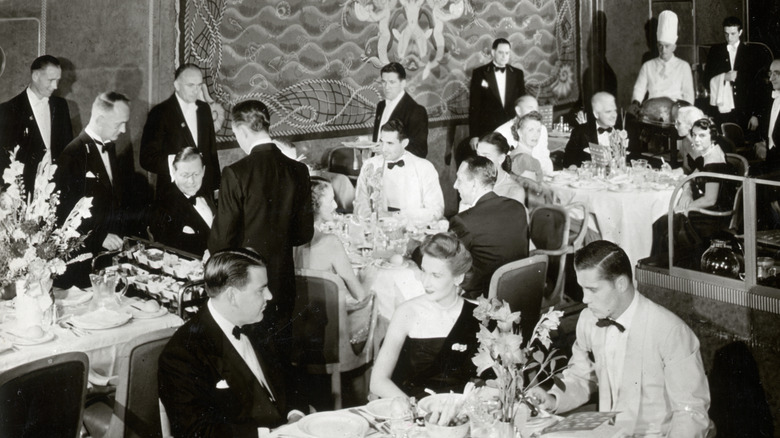 A formal dining room In the right background, one of the chefs can be seen.