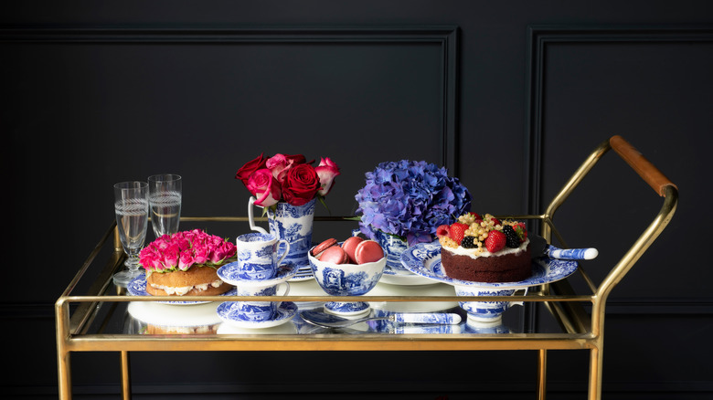 Dessert trolley laden with cakes, tea cups, and flowers in vases