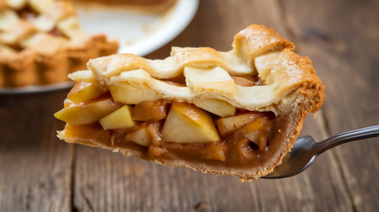 A slice of apple pie rests on a pie server