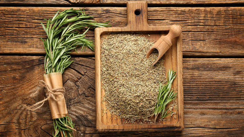Fresh and dried rosemary on wooden background