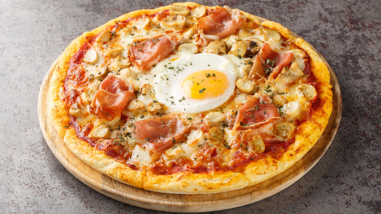 A fried egg on a pizza with mushrooms and prosciutto