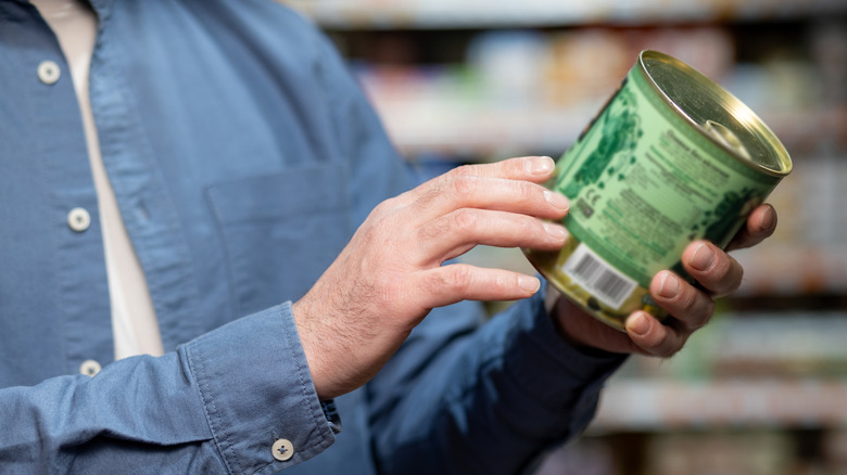 A shopper examining a can of food.