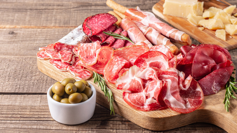 Wooden charcuterie board covered in meats.