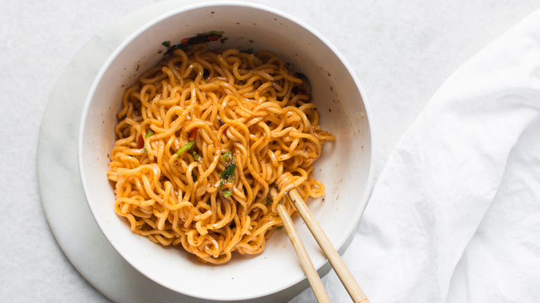 A bowl of instant ramen with chopstick resting on the side.