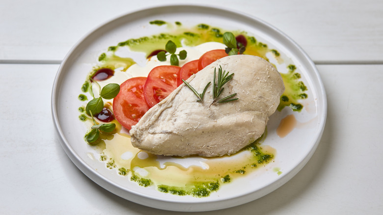 Poached chicken on plate with vegetables and sauces