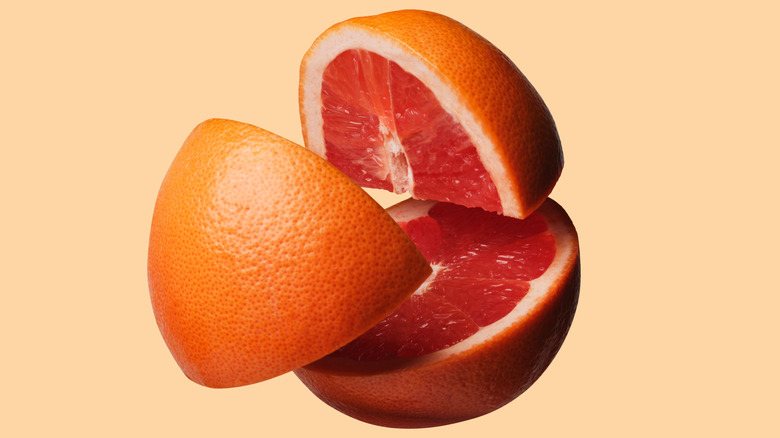 Grapefruit cut into three sections on an orange background.