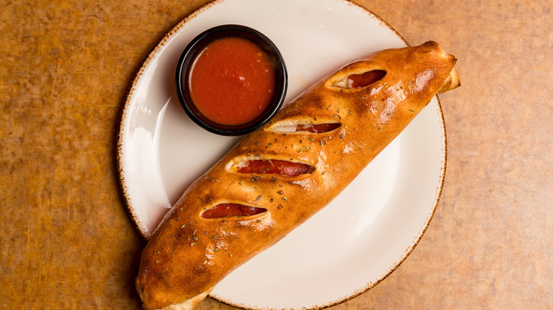 Italian stromboli with a dish of marinara sauce