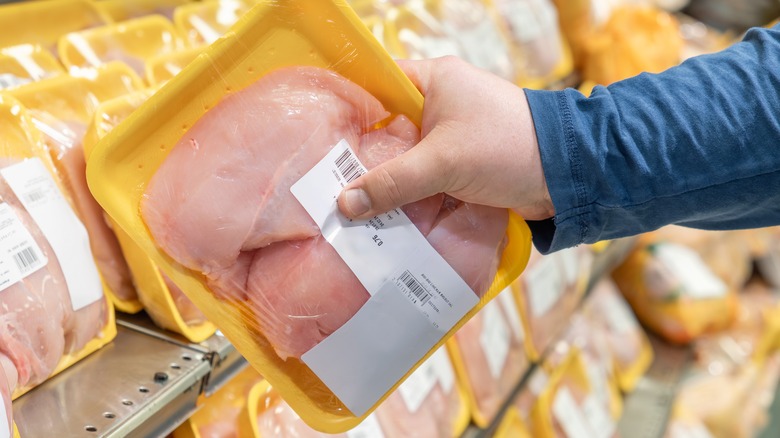 A man choosing chicken breast filets from the grocery store