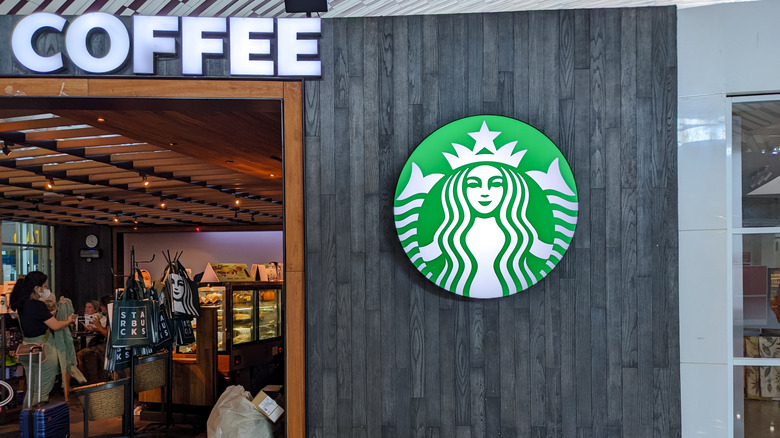 A Starbucks sign on a wooden wall outside the store