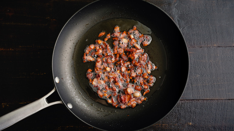 Top view of diced bacon rendering in dark pan