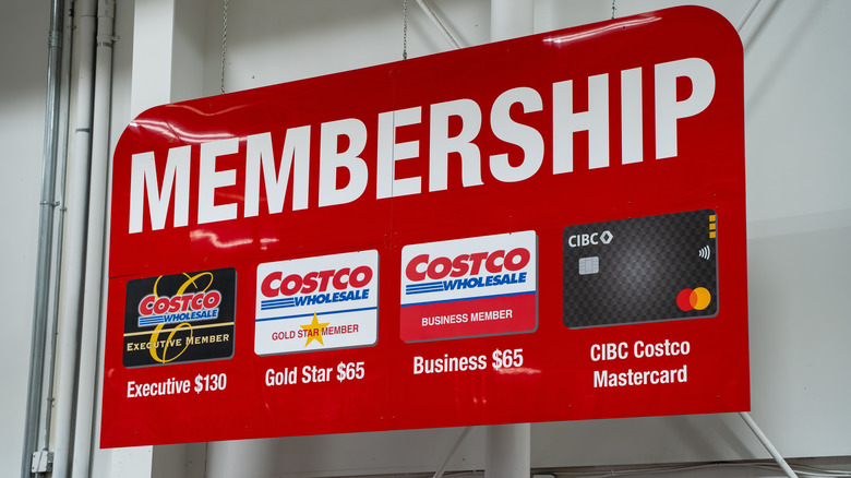 A sign above a Costco membership desk with images of the various membership cards.