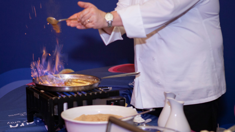 A chef prepares flaming bananas Foster in a tableside pan