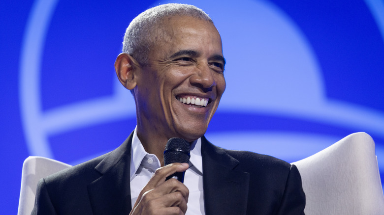 Barack Obama shown smiling while holding a microphone