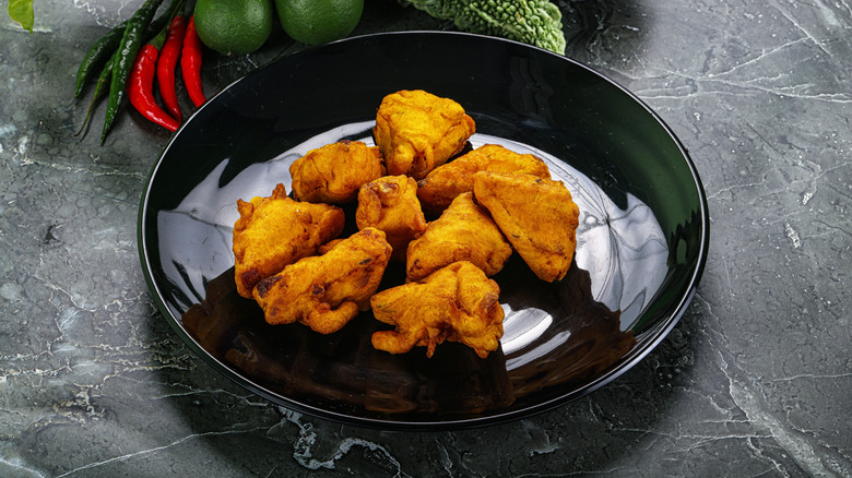 Paneer pakora on a black plate on a marbled surface