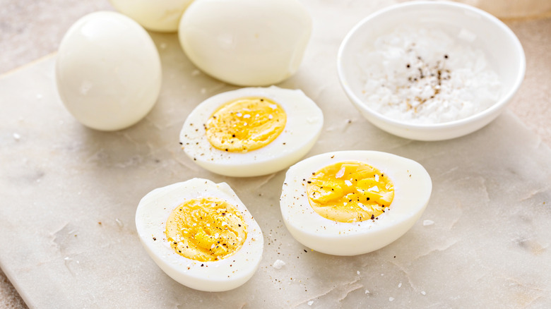 Boiled eggs whole and cut in half served with salt and pepper