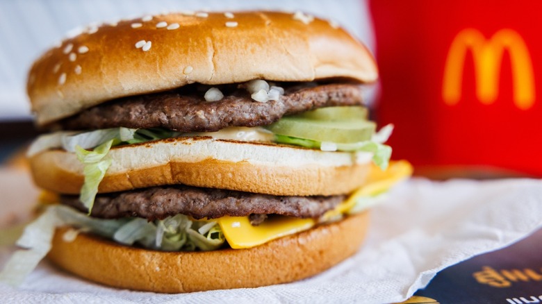 A closeup of a Big Mac burger on a tray with a red McDonald's fry box in the background.